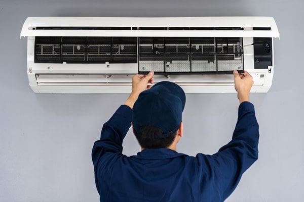 Technician cleaning and repairing air conditioner.